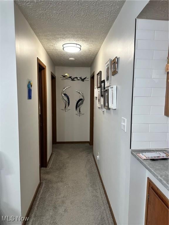 hallway with light colored carpet and a textured ceiling