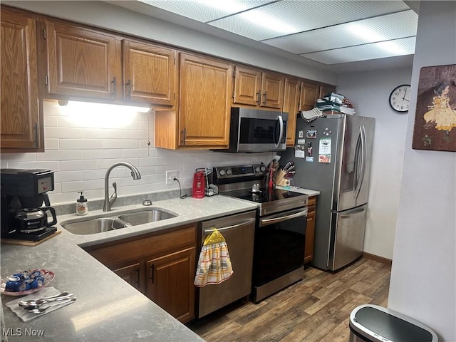 kitchen with sink, hardwood / wood-style flooring, decorative backsplash, and appliances with stainless steel finishes