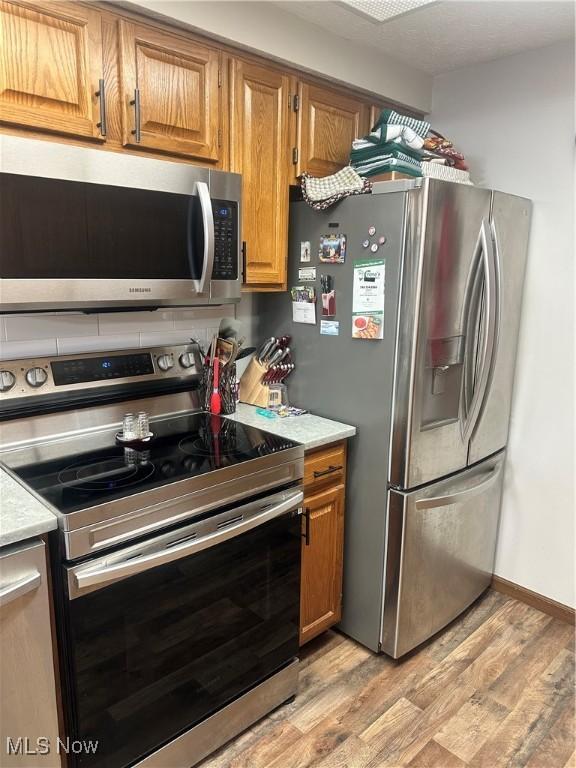 kitchen with light hardwood / wood-style flooring and appliances with stainless steel finishes