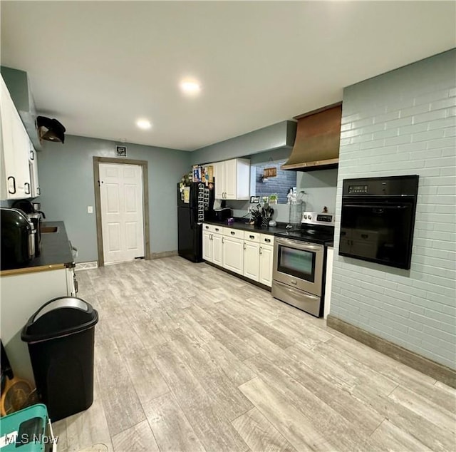 kitchen with light hardwood / wood-style flooring, black appliances, wall chimney exhaust hood, and white cabinets