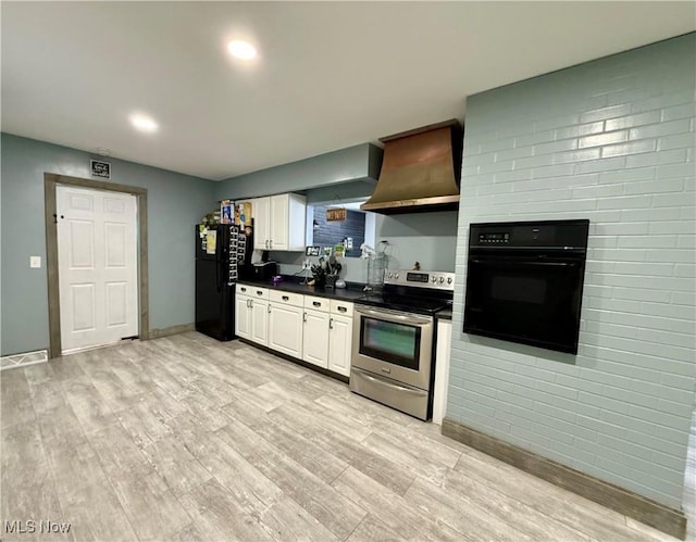 kitchen with white cabinetry, light hardwood / wood-style flooring, wall chimney range hood, and black appliances