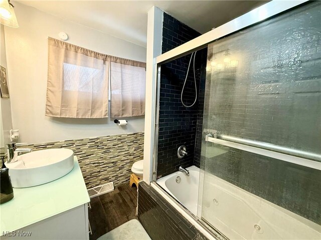 full bathroom with toilet, combined bath / shower with glass door, tile walls, vanity, and hardwood / wood-style flooring