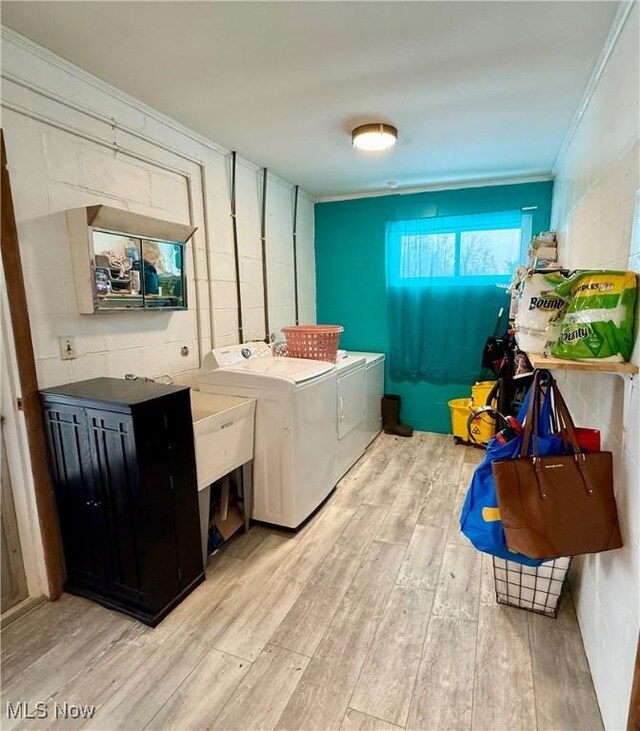 washroom with crown molding, independent washer and dryer, and light hardwood / wood-style flooring