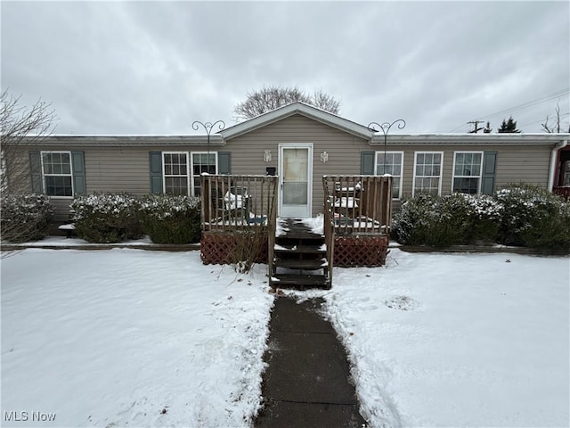 snow covered back of property with a deck