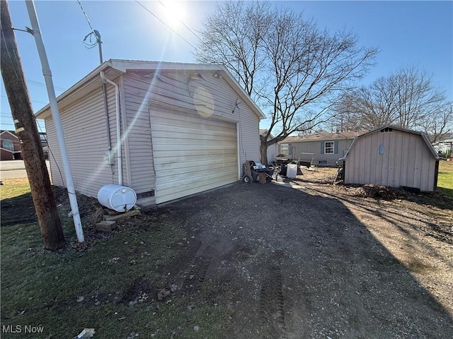 view of home's exterior with an outdoor structure, a shed, a detached garage, and driveway