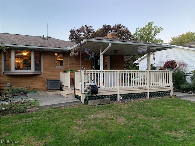 back of property with a yard, a patio, and a wooden deck