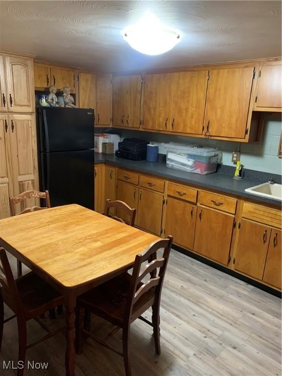 kitchen with black refrigerator, light wood-type flooring, and sink