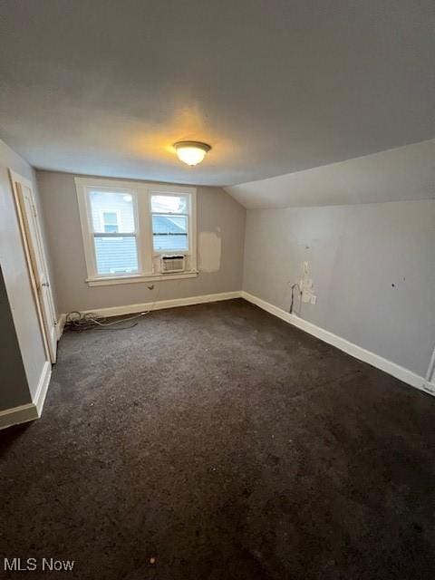 additional living space featuring dark colored carpet and vaulted ceiling