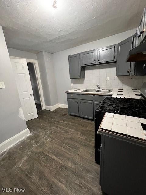 kitchen with dark hardwood / wood-style flooring, backsplash, gray cabinetry, ventilation hood, and sink