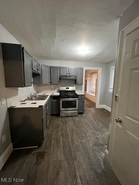 kitchen featuring sink, dark hardwood / wood-style flooring, backsplash, gray cabinets, and stainless steel stove