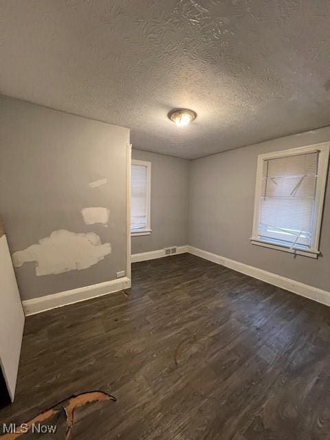 unfurnished room featuring dark wood-type flooring and a textured ceiling