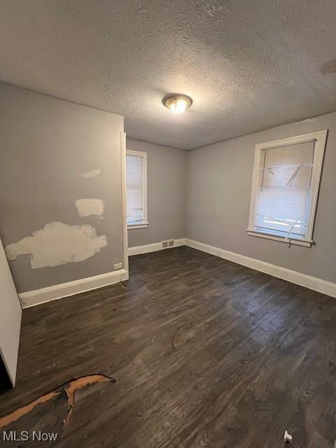 empty room with a textured ceiling and dark wood-type flooring