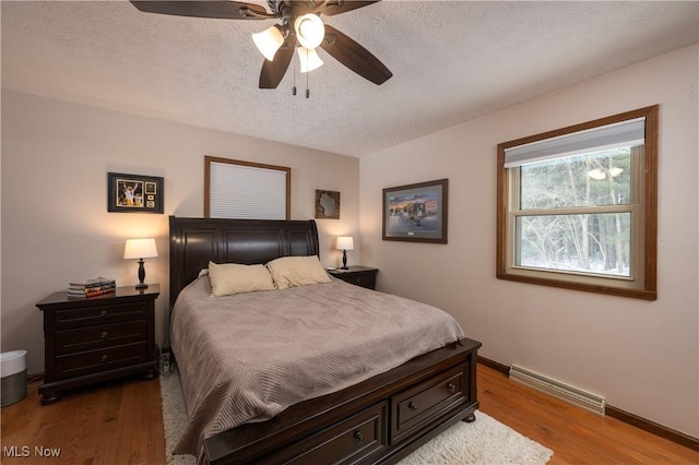 bedroom with ceiling fan, wood-type flooring, and a textured ceiling