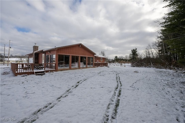 snow covered property with a sunroom and a wooden deck