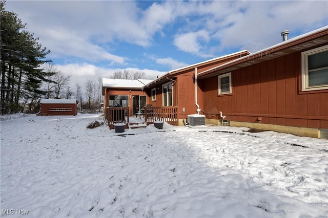 snow covered back of property with a wooden deck and central air condition unit