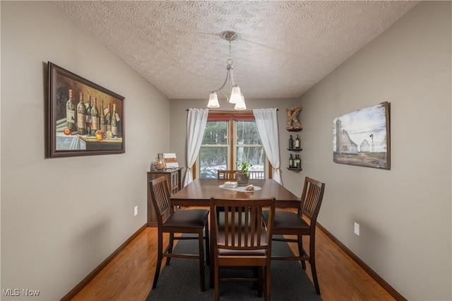 dining area featuring hardwood / wood-style floors, a textured ceiling, and an inviting chandelier