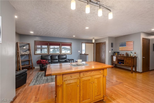 kitchen featuring wood counters, light hardwood / wood-style floors, a kitchen island, and a textured ceiling