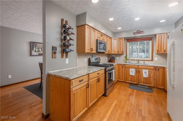 kitchen featuring light stone counters, sink, a textured ceiling, and appliances with stainless steel finishes