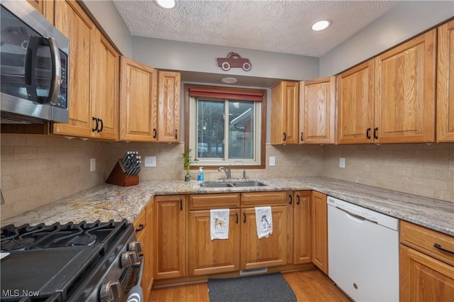 kitchen with light stone countertops, sink, backsplash, white dishwasher, and a textured ceiling