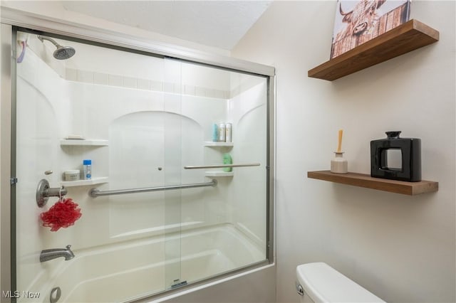 bathroom featuring toilet, enclosed tub / shower combo, and a textured ceiling