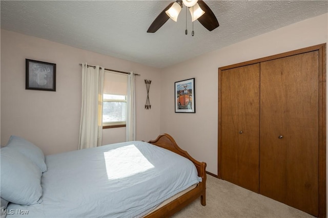 carpeted bedroom with ceiling fan, a textured ceiling, and a closet