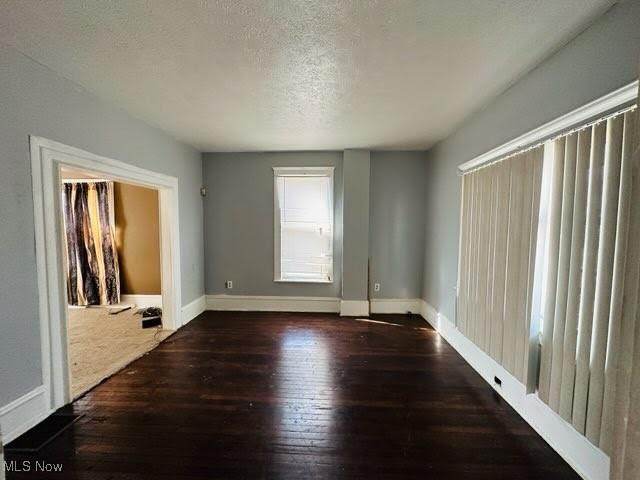 empty room with a textured ceiling and dark hardwood / wood-style floors