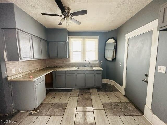 kitchen with tasteful backsplash, a textured ceiling, ceiling fan, sink, and gray cabinets