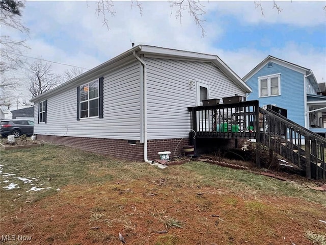 view of property exterior featuring a wooden deck and a lawn