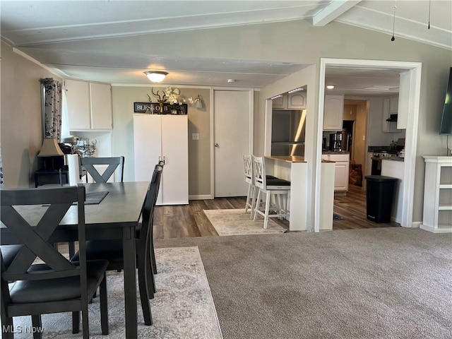 dining area featuring dark colored carpet and vaulted ceiling with beams