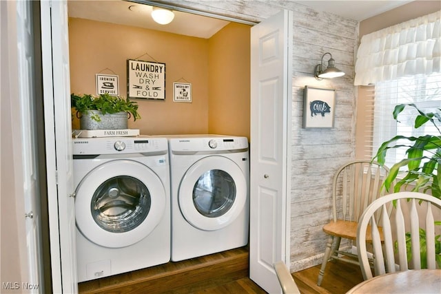 laundry room featuring separate washer and dryer, wood walls, and dark wood-type flooring