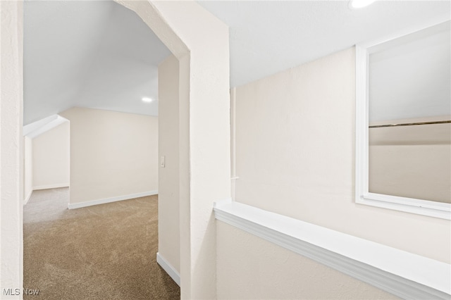 hallway with light colored carpet and vaulted ceiling