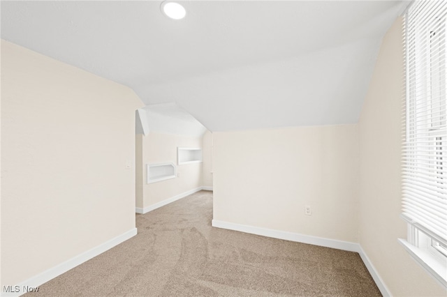 additional living space with light colored carpet and lofted ceiling