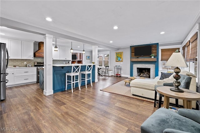 living room with hardwood / wood-style floors, a brick fireplace, and crown molding