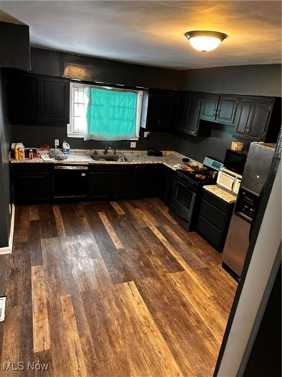 kitchen featuring stove, sink, dark hardwood / wood-style floors, black dishwasher, and light stone counters