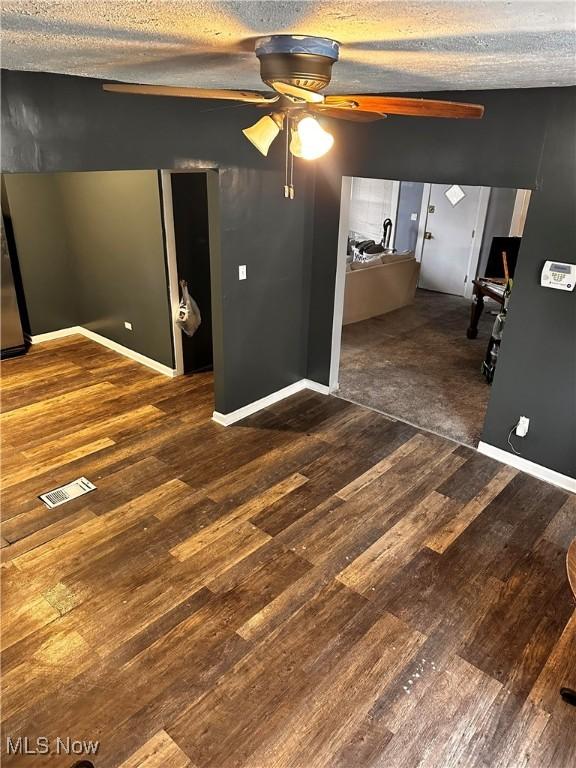 empty room featuring ceiling fan, a textured ceiling, and dark wood-type flooring