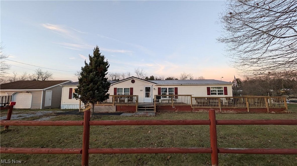 view of front of home with a lawn, a garage, a deck, and an outbuilding