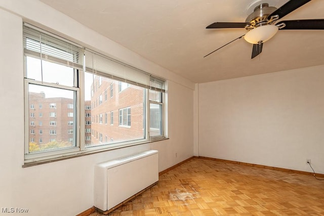 spare room featuring light parquet flooring, radiator, and ceiling fan