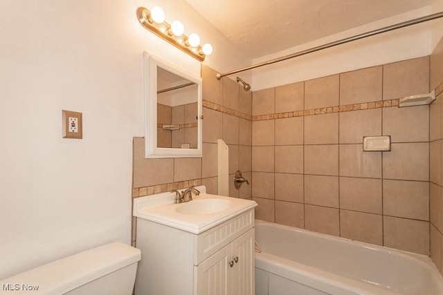 full bathroom with vanity, toilet, backsplash, and tiled shower / bath