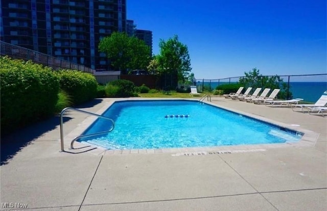 view of swimming pool featuring a water view and a patio