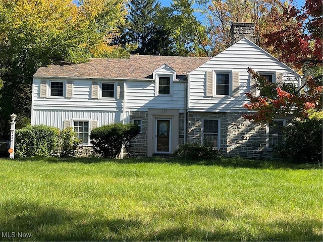 view of front facade featuring stone siding, a chimney, and a front yard