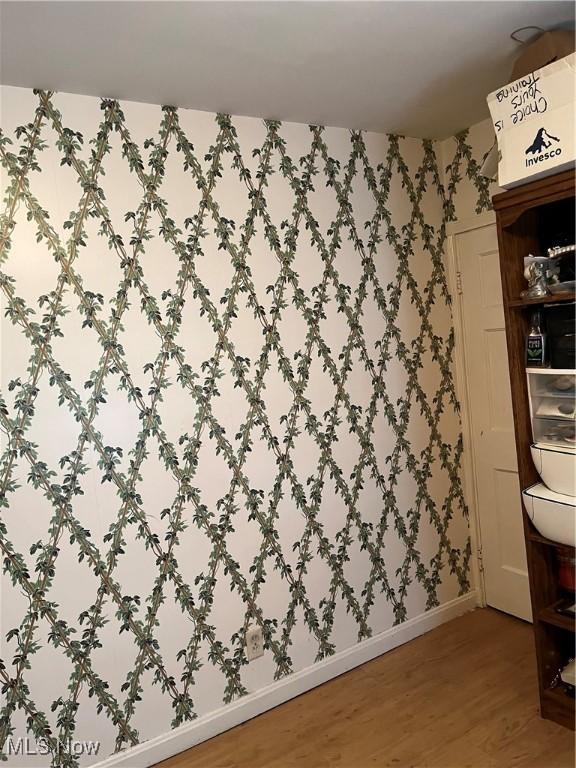 interior space featuring wallpapered walls, baseboards, and wood finished floors