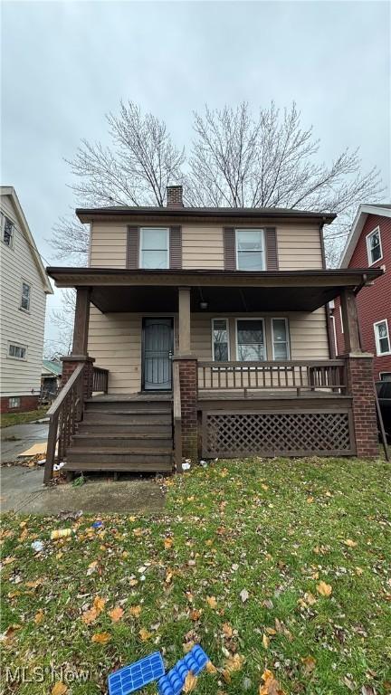 back of house featuring covered porch and a lawn