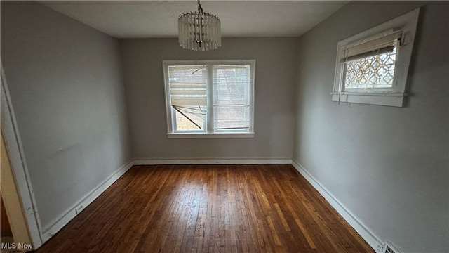 unfurnished dining area with a notable chandelier and dark hardwood / wood-style flooring