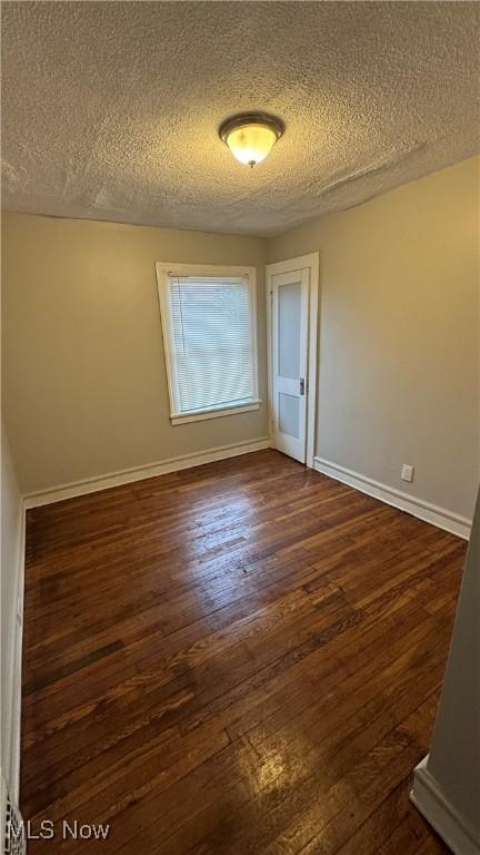 unfurnished room with dark hardwood / wood-style flooring and a textured ceiling