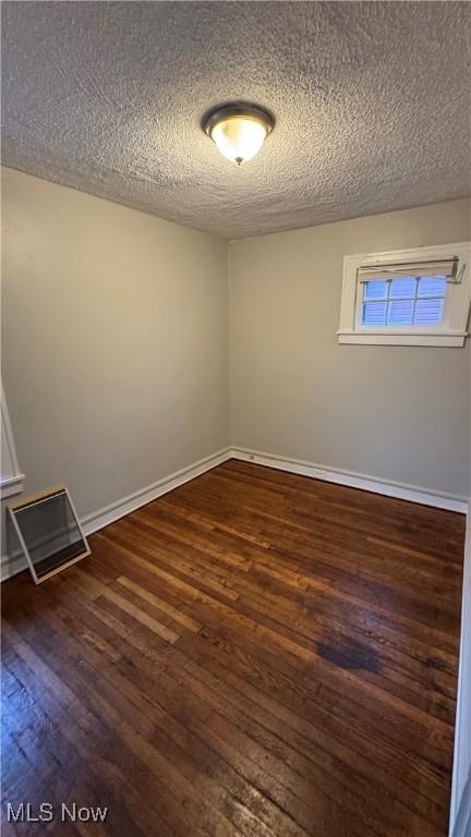 unfurnished room featuring a textured ceiling and dark wood-type flooring