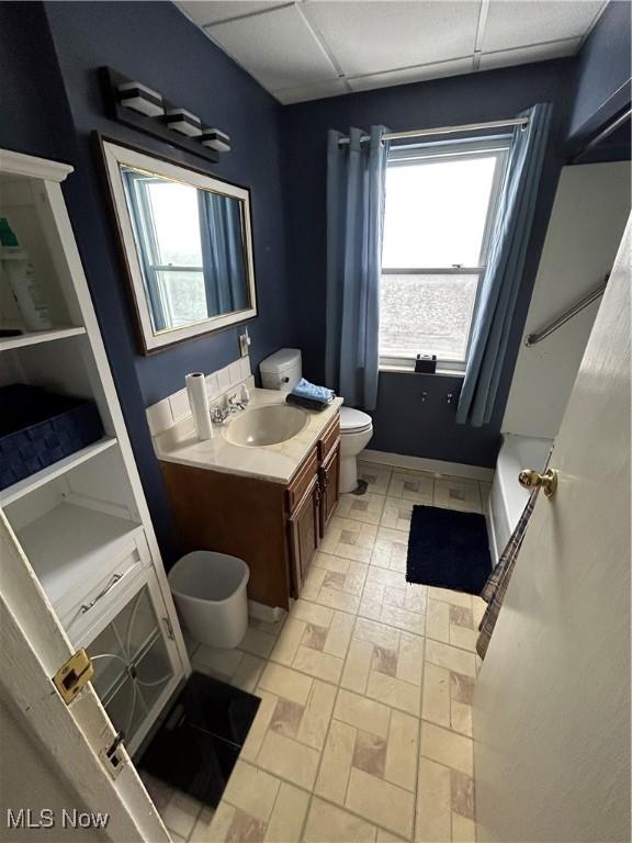 bathroom with a paneled ceiling, vanity, and toilet