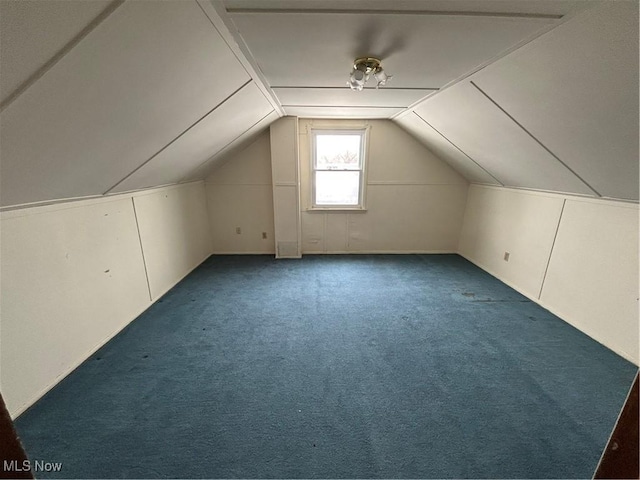 additional living space with dark carpet and vaulted ceiling