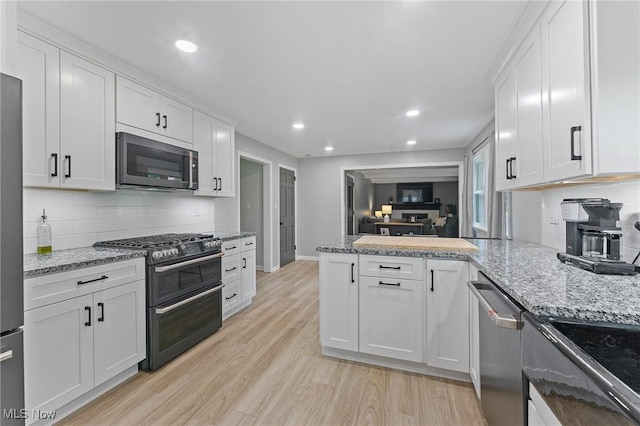 kitchen featuring light stone countertops, backsplash, stainless steel appliances, light hardwood / wood-style flooring, and white cabinetry