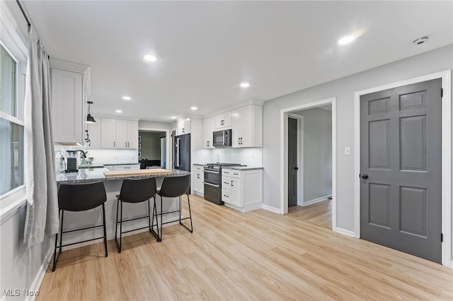 kitchen with high end fridge, white cabinets, and stainless steel range with gas stovetop