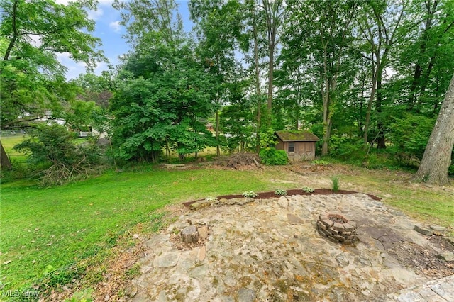 view of yard featuring a patio, a fire pit, and a storage shed